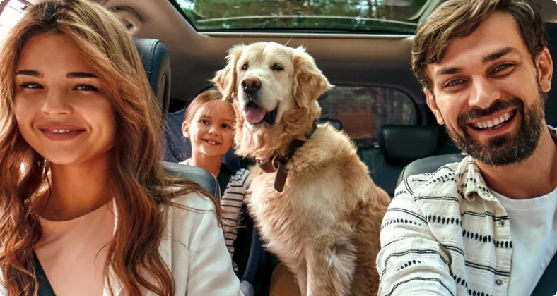 Eine glückliche Familie mit einem Golden Retriever sitzt lächelnd im Auto, bereit für einen gemeinsamen Ausflug oder eine Reise.