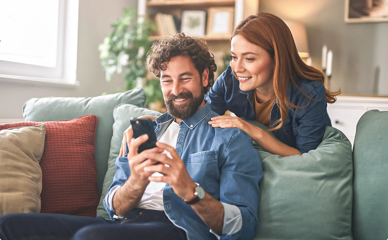 Zwei Personen auf dem Sofa schauen aufs Handy 