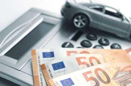 Taschenrechner, Spielzeugauto und Euro-Geldscheine symbolisieren Autofinanzierung und Fahrzeugkosten.