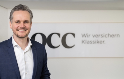 Ein Mann im Sakko vor dem Schriftzug "OCC" - Marcel Neumann, Chief Market Officer