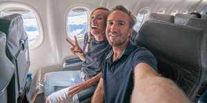 Urlaubsfeeling, ein Pärchen macht Selfies von sich im Flugzeug.
