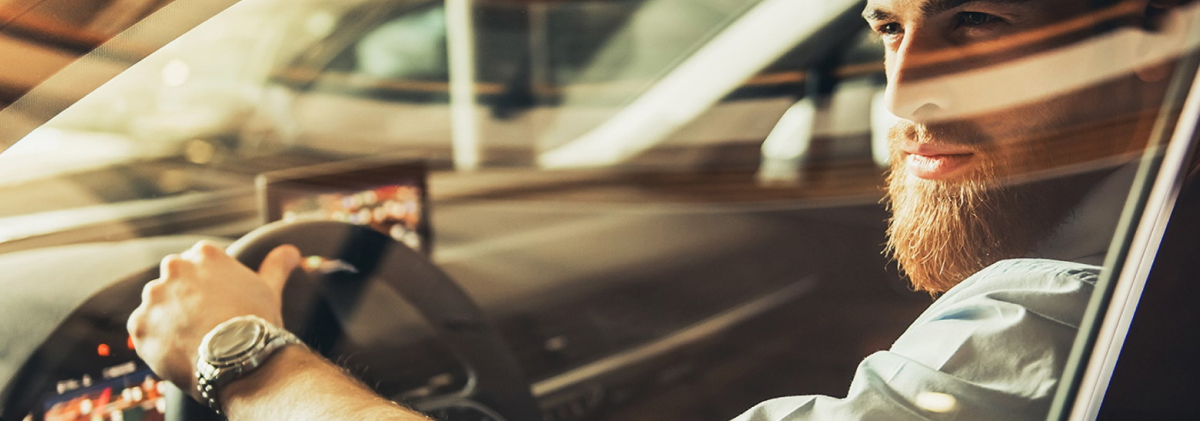 Bärtiger Mann sitzt entspannt im Auto, symbolisiert Sicherheit und Freiheit.