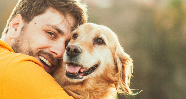 Lachender junger Mann mit seinem Hund.