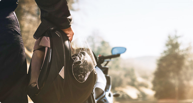 Ein Mann steht mit seinem Motorradhelm vor seinem Motorrad.