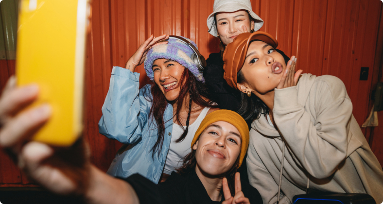 Vier Teenager Mädchen posieren lustig für eine Selfie Aufnahme mit dem Handy.