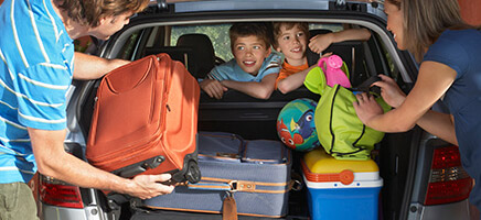 Eine Familie packt alle Koffer in den Kofferraum ihres Autos.
