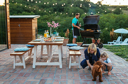 Eine Familie bereitet auf der Terrasse einen Grillabend vor.