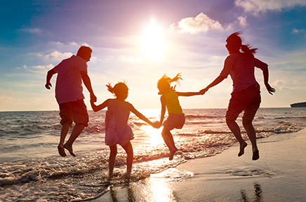 Familie spielt im Sonnenuntergang am Strand.