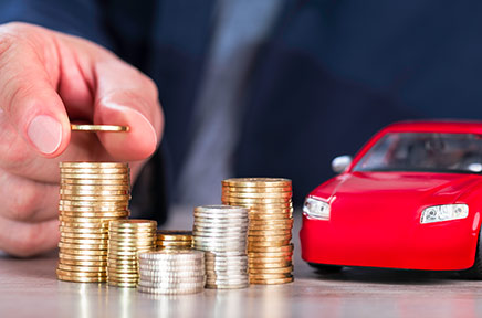 Der Autorückkauf wird beispielhaft mit einem Modellauto und Geld veranschaulicht.