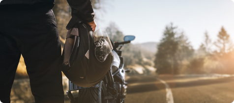 Ein Mann steht mit seinem Motorradhelm vor seinem Motorrad.