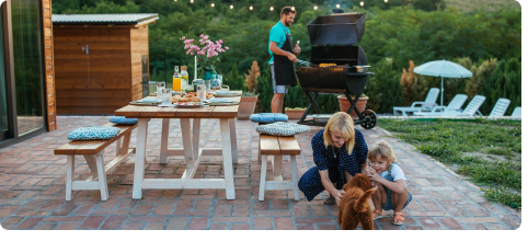 Eine Familie bereitet auf der Terrasse einen Grillabend vor.